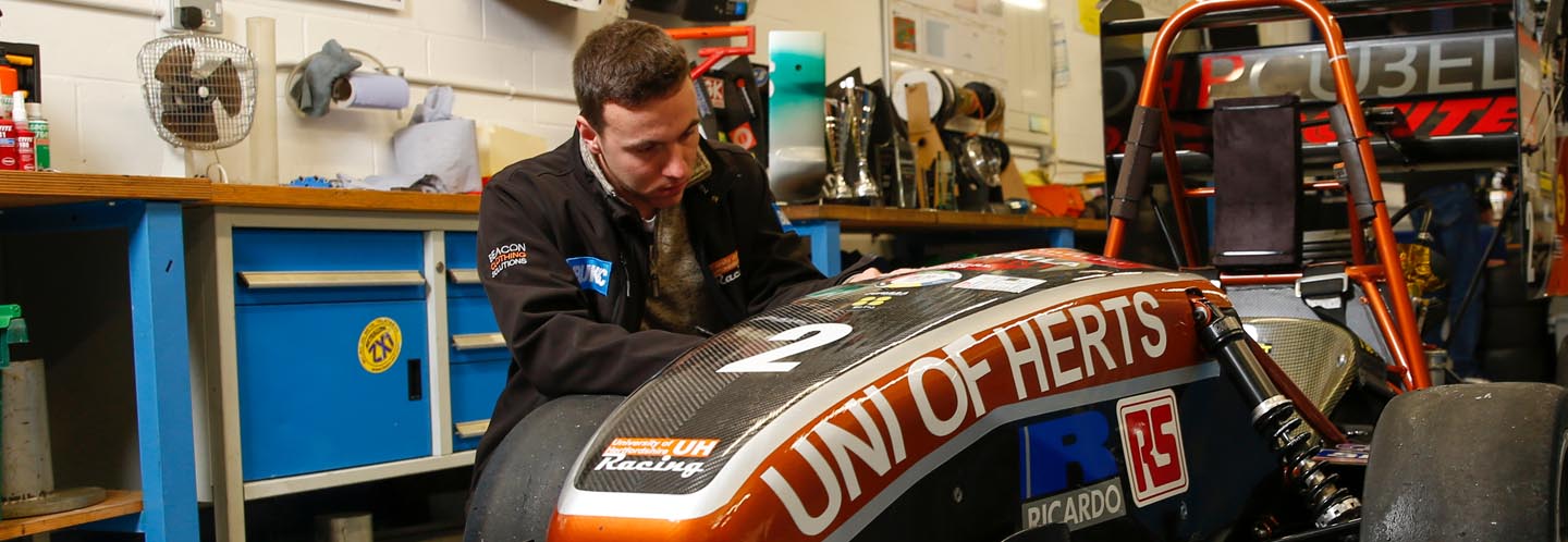 Student working on car in garage