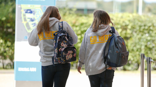 Two female students walking down path away from camera