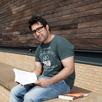 male student sits on wall reading