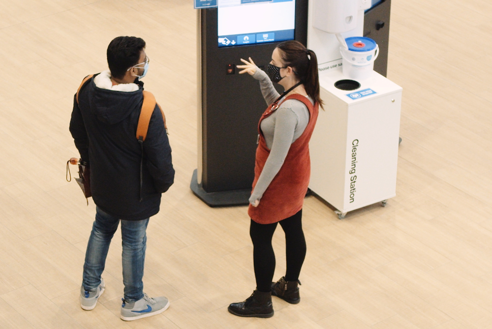 Female helping student with face mask