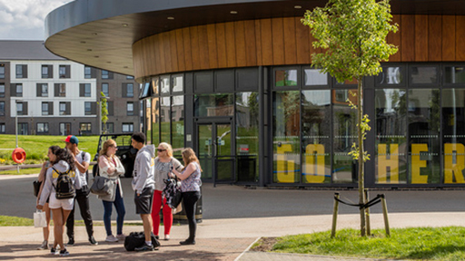 a group of students talk outside The Oval on a sunny day