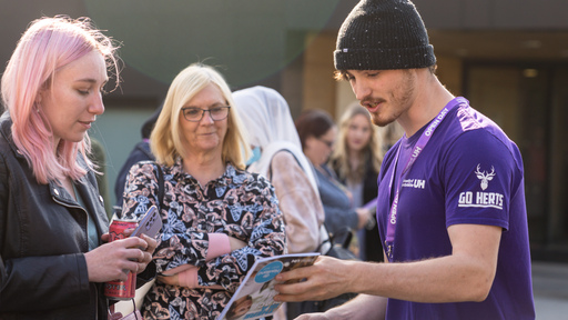 Image of a Herts student talking to visitors at open day