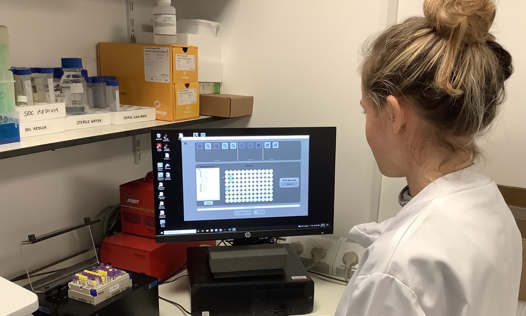 Female in white lab coat looking at a computer screen