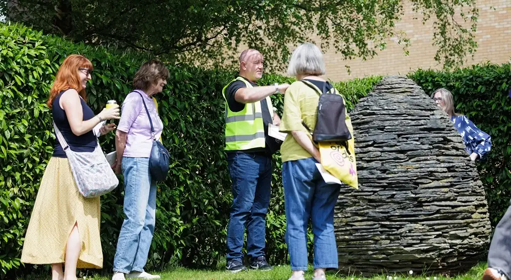 A guided tour with people looking at a sculpture