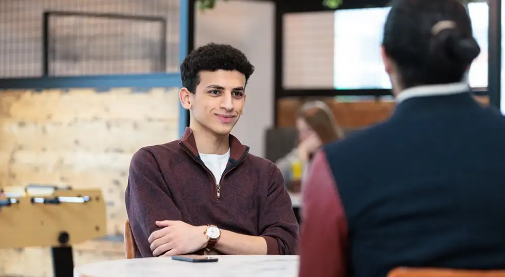 2 people talking around table