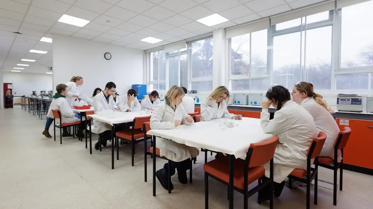 A group of students in lab coats sitting at desks