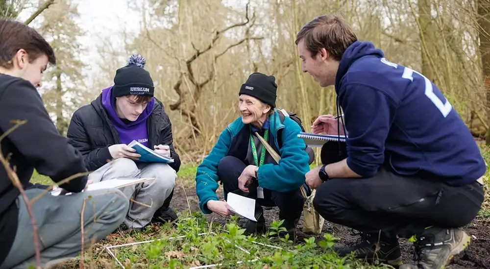 Students and lecturer outside in the woods smiling