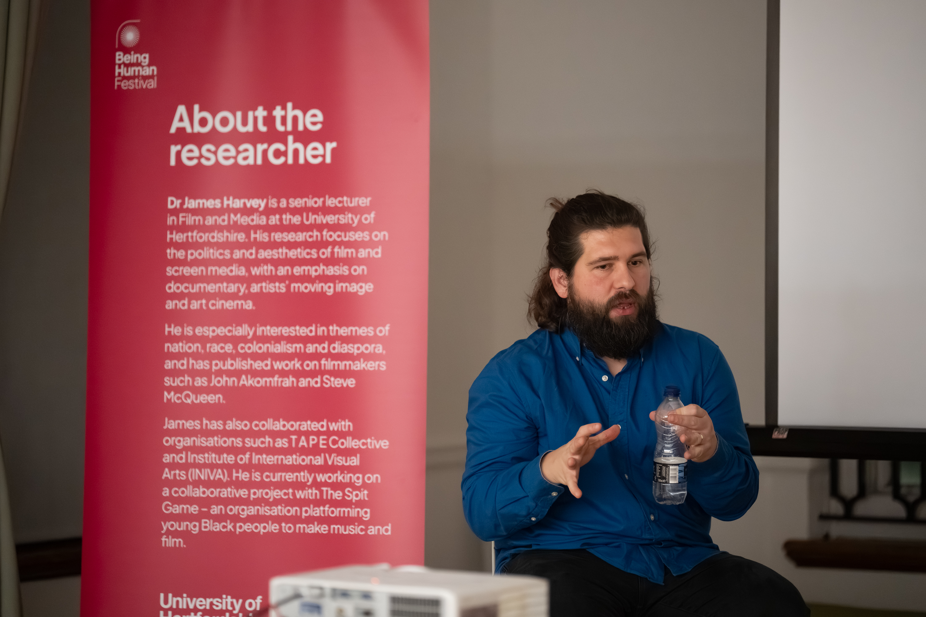 Man presenting in front of a red banner 