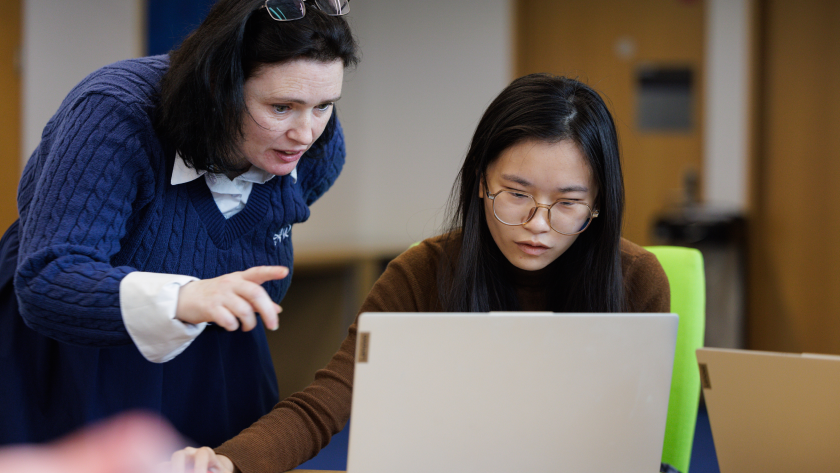 A lecturer looking over the shoulder of a student