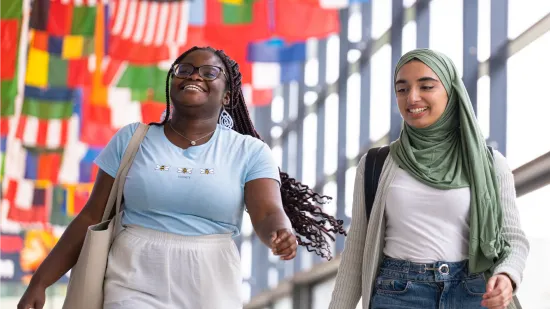 Two student smiling with flags behind them