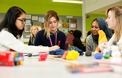 Group of students sitting around table with childrens toys