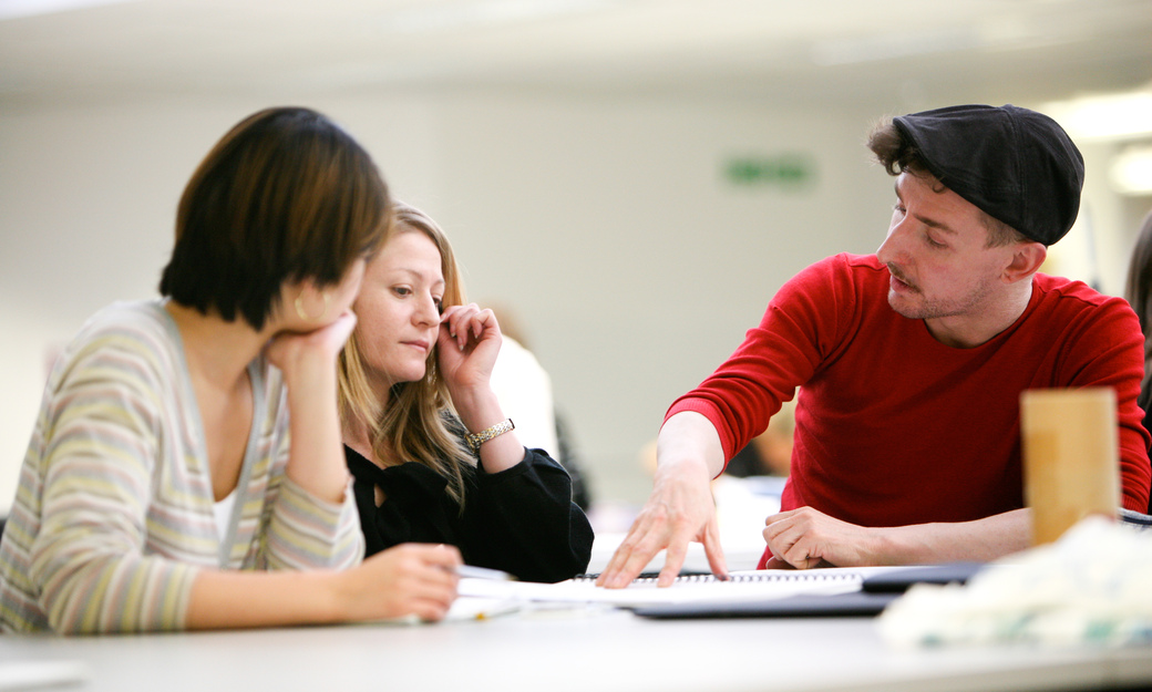 three students sitting on the grass, studying in the sunshine