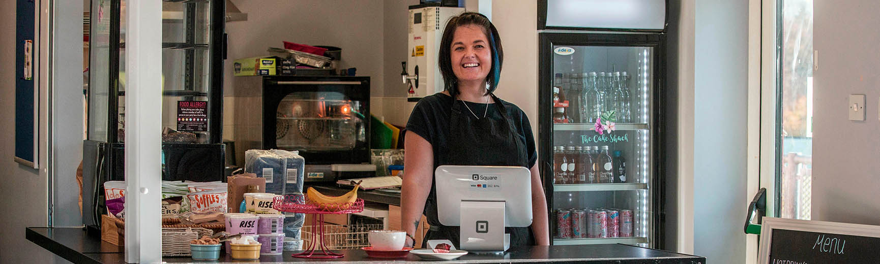 Owner of small cafe in Herts standing behind counter