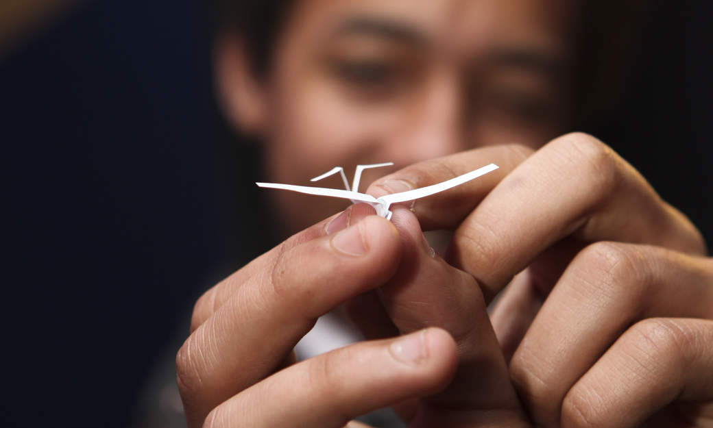 a student holding a miniture model aeroplane that they created 