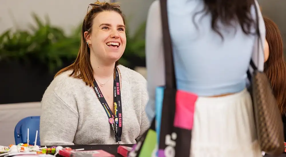 A person sitting behind a desk smiling and talking to a student