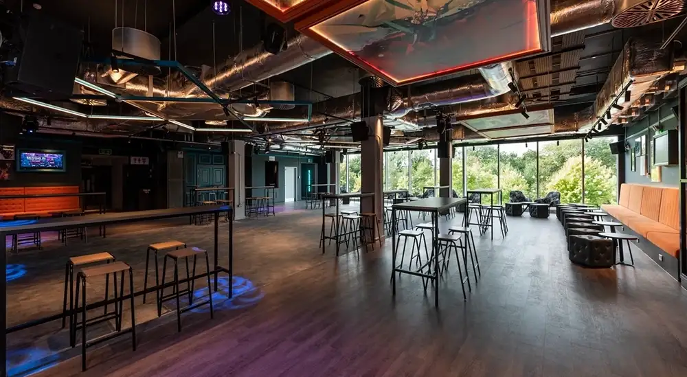 A open plan room with three high tables and chairs around each table and bench seating in a corner of the room