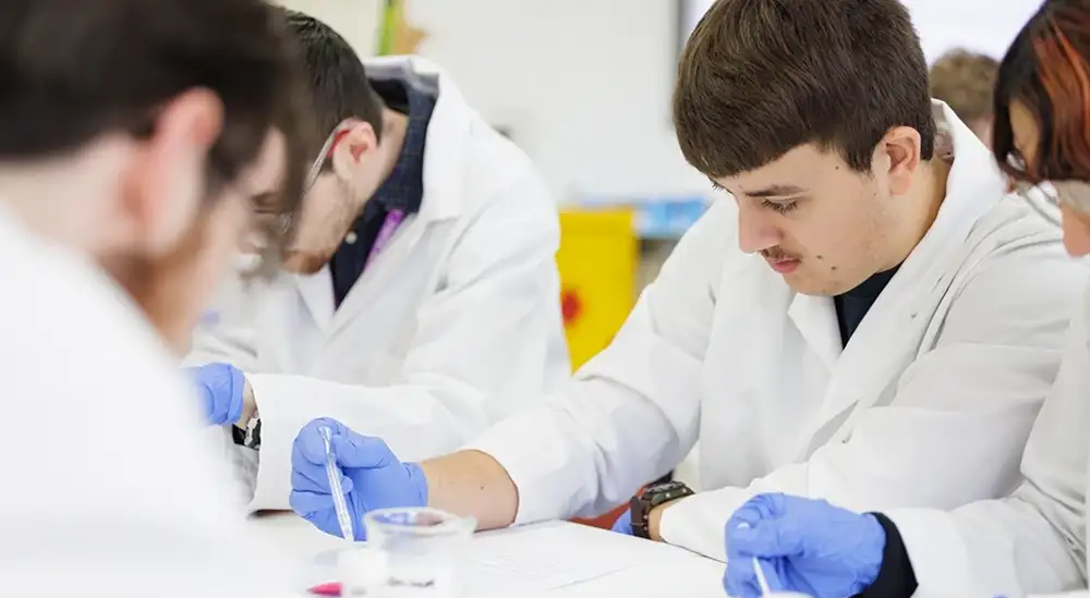 A student in a lab coat working with a pipet