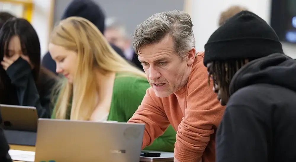 A lecturer talking to a student pointing at a laptop screen