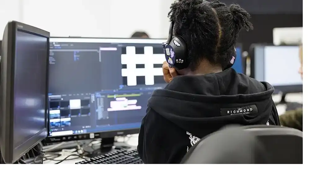 A student working at a computer with headphones on