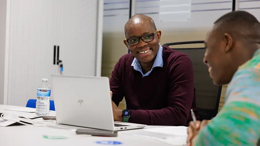 A lecturer talking to a student with a laptop open
