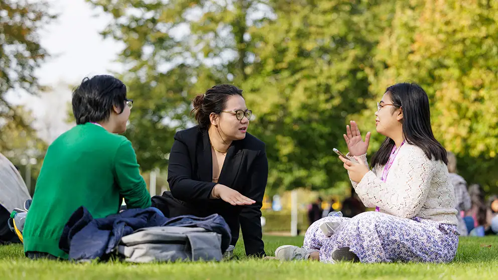 Three people sitting on grass