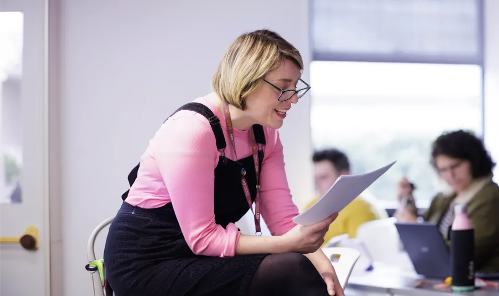 A lecturer talking to students from a paper