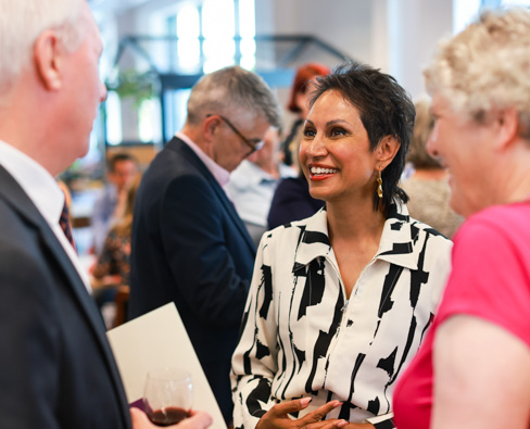Two females and a male talking at a drinks reception