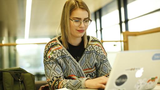 White female student studying on Mac laptop