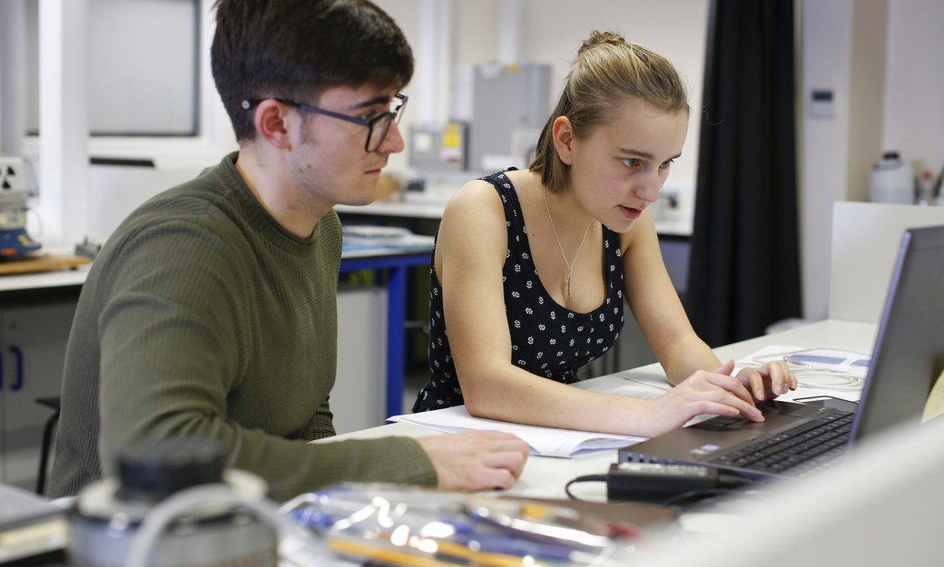 two students completing a project on a laptop 