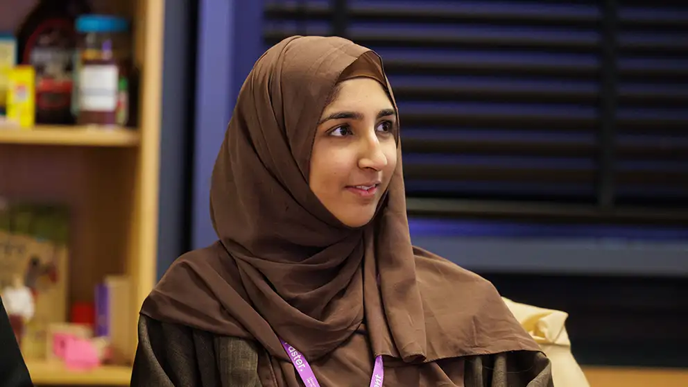 A student in a head scarf listening to a lecturer