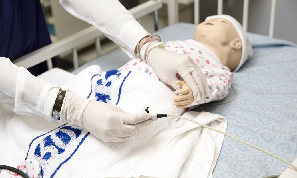 A student nurse putting a heart monitor on a child mannequin 