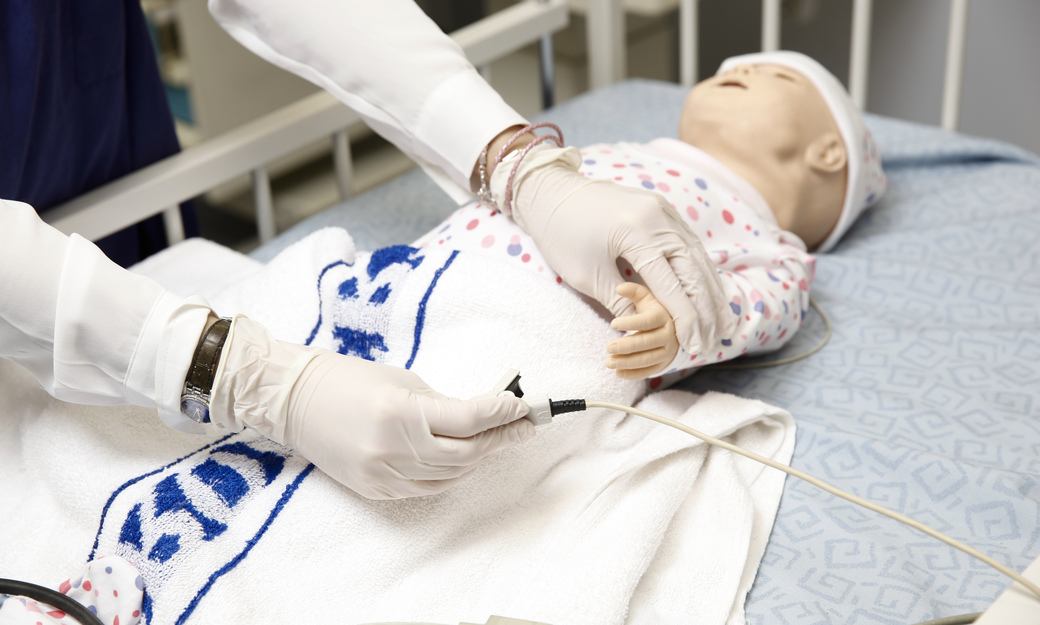 A student nurse putting a heart monitor on a child mannequin