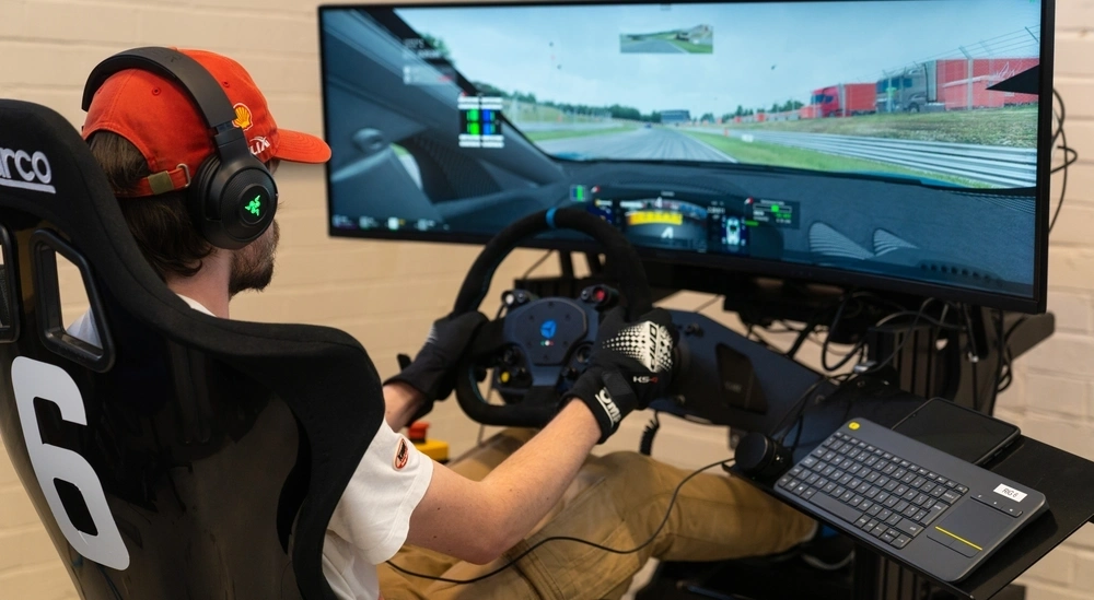 A student in a racing car simulation wearing a hat