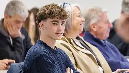 A student sitting down next to a guardian or parent