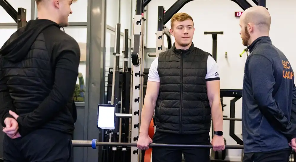 people guiding someone on how to lift weight