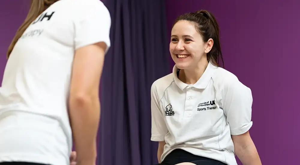 A student smiling while sitting up