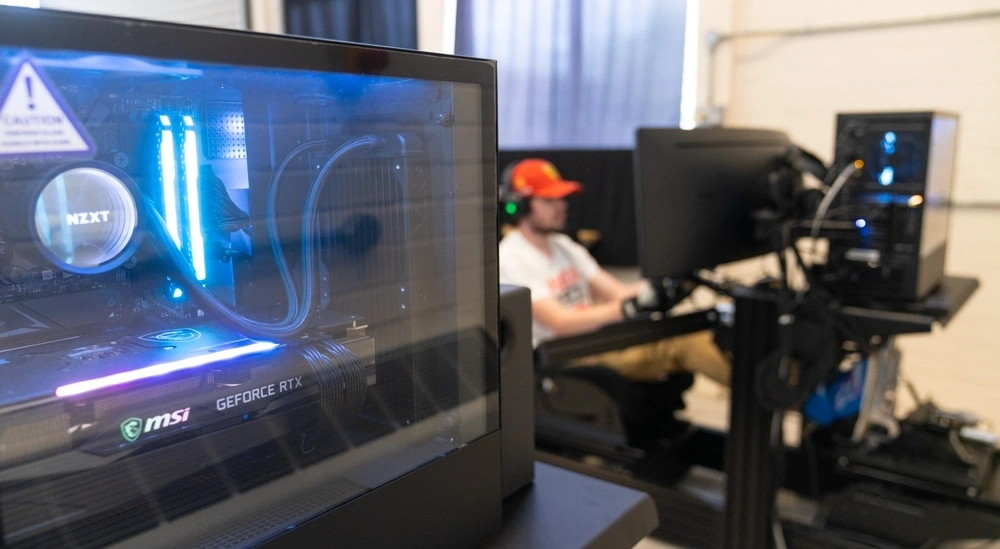 A student in a racing seat simulation with a server in the foreground