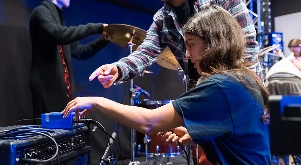 A student plugging in sound equipment