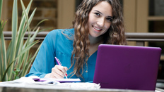 A smiling student with a laptop