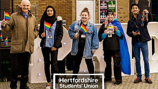 Vice Chancellor, Quintin McKellar waves a rainbow flag with members of the LGBT+ Society at Herts 