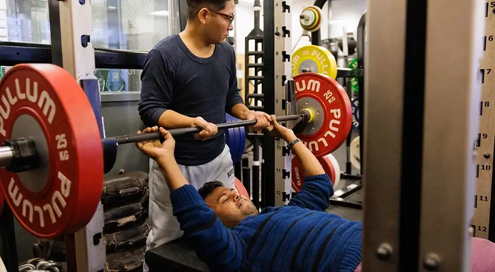 Person guiding someone on how to lift weight
