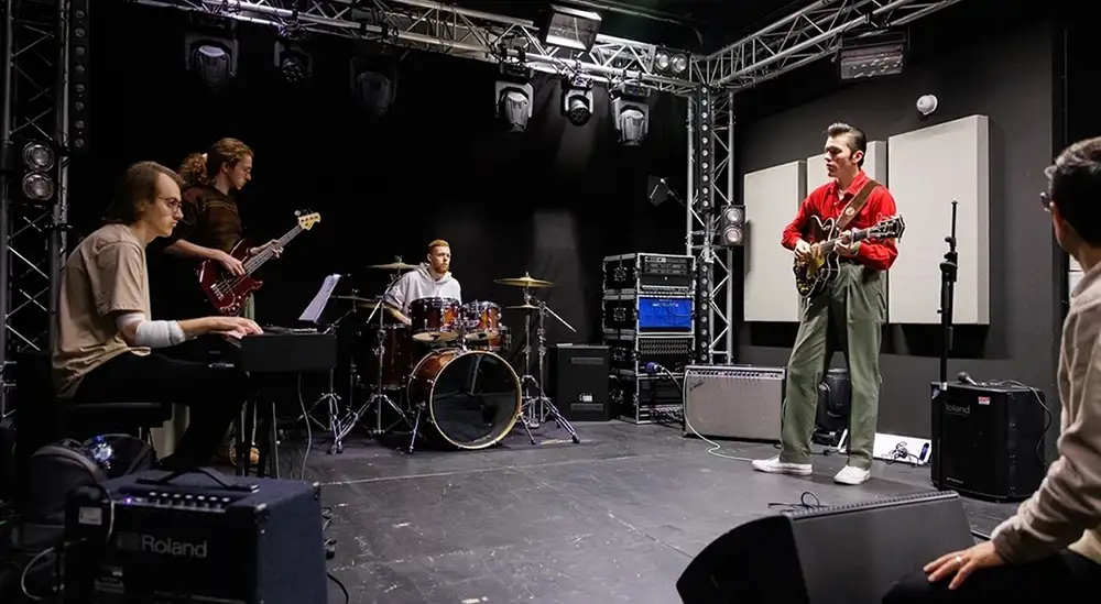 A studnet playing a guitar as part of a band