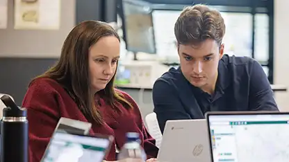 Two student looking at a laptop screen working